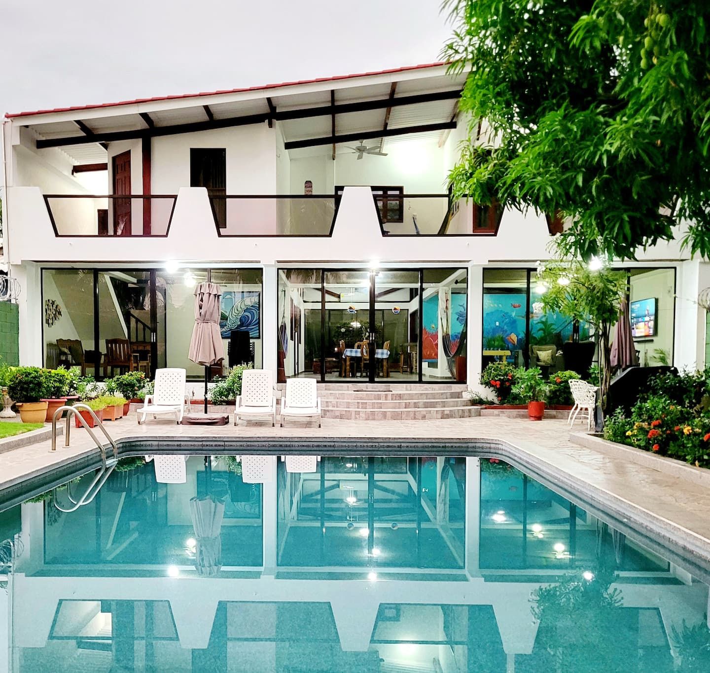 El Cocal at dusk: a white two-storey house lit from inside, its pool reflecting the lights
