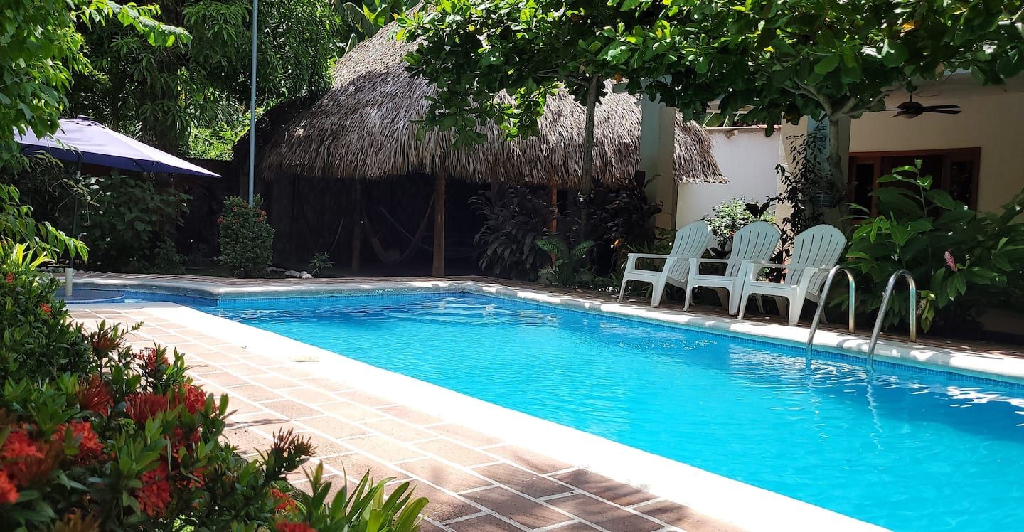 El Sunzal: a turquoise pool in front of a thatched-roof rancho surrounded by trees